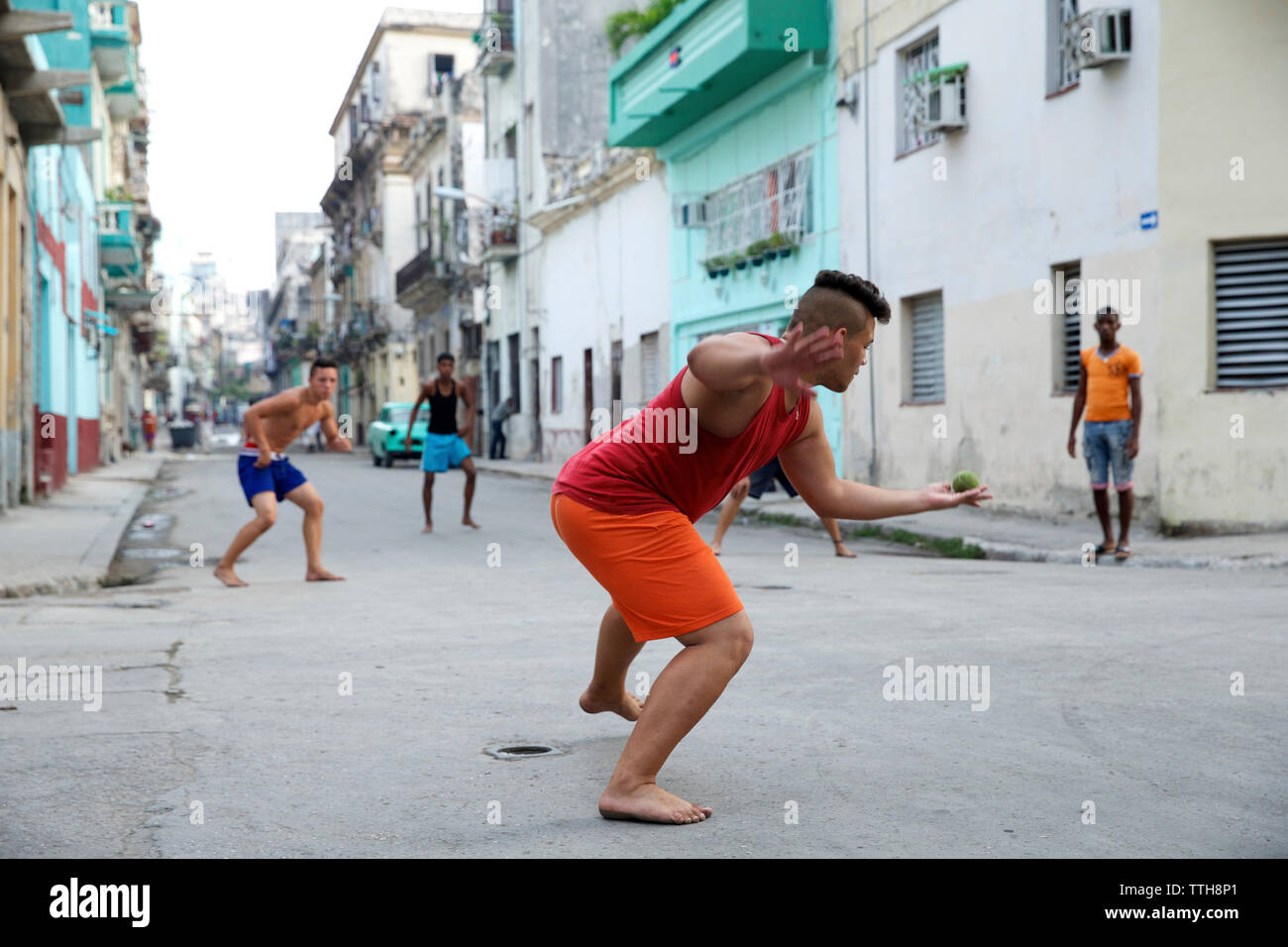 Amis jouant avec balle sur rue en ville Banque D'Images
