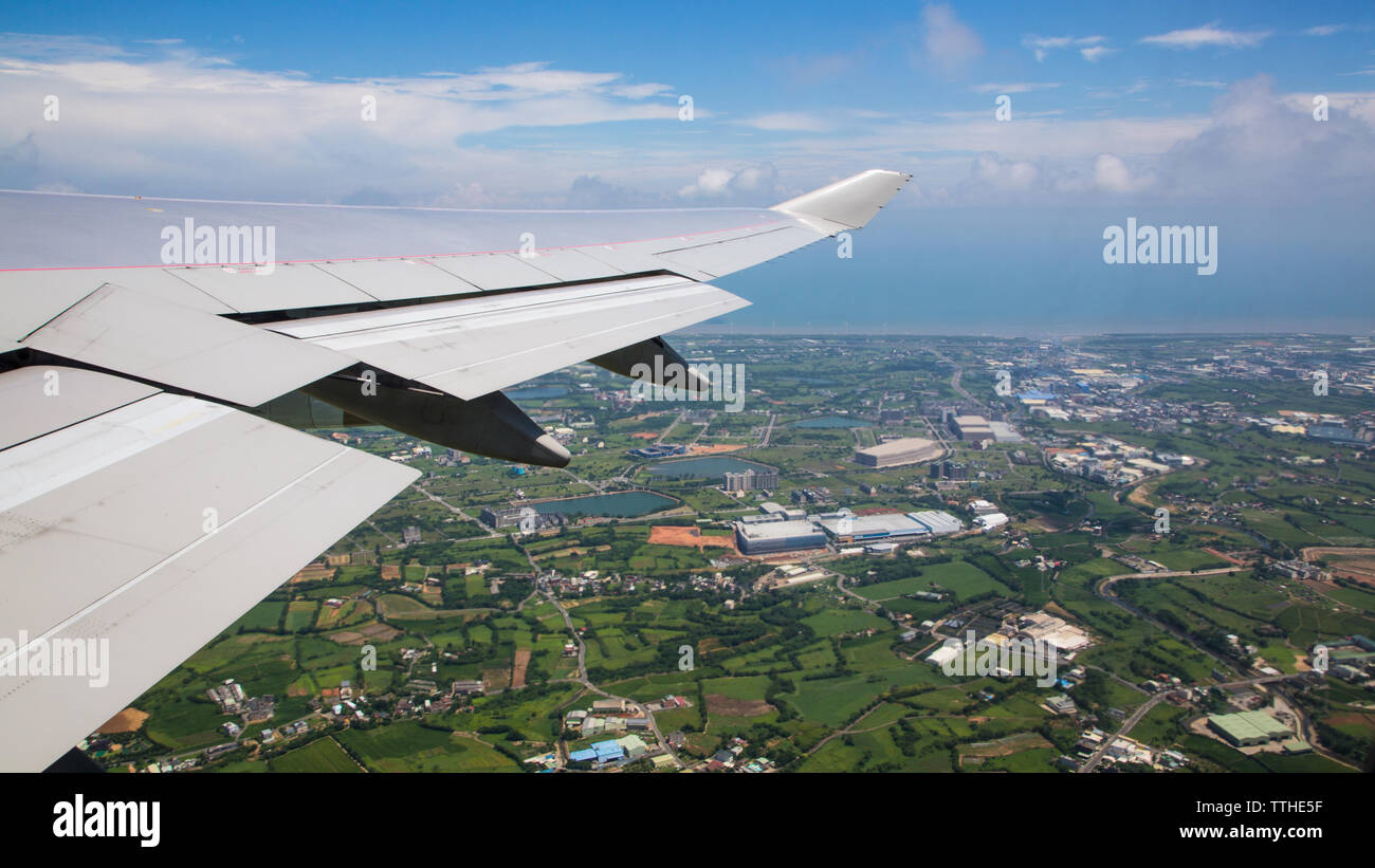 Vous voyagez par avion. Vue aérienne d'une ville à l'île de Taiwan. Voir l'aile de l'avion et la ville de Taoyuan en arrière-plan comme vu à travers une fenêtre. Banque D'Images