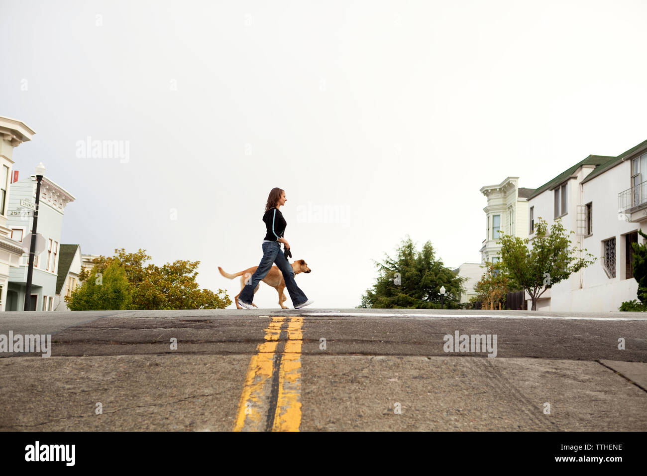 Vue de côté de la femme et de dog walking on street Banque D'Images