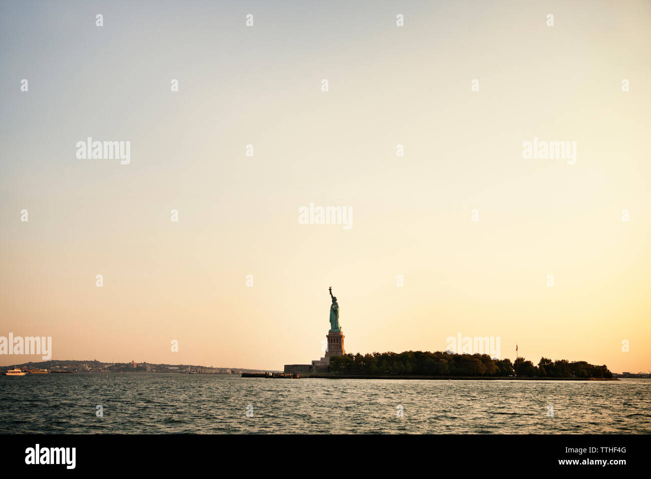 Vue sur la rivière et de la Statue de la liberté dans la ville contre le ciel au coucher du soleil Banque D'Images
