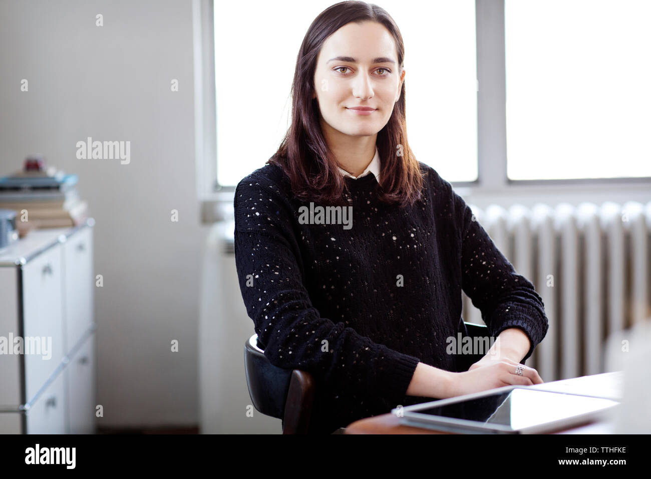 Portrait of businesswoman sitting on chair in creative office Banque D'Images