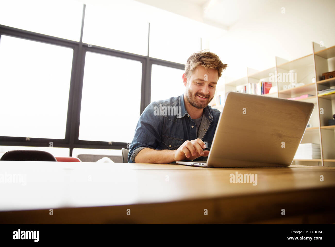 Happy man using laptop at table Banque D'Images