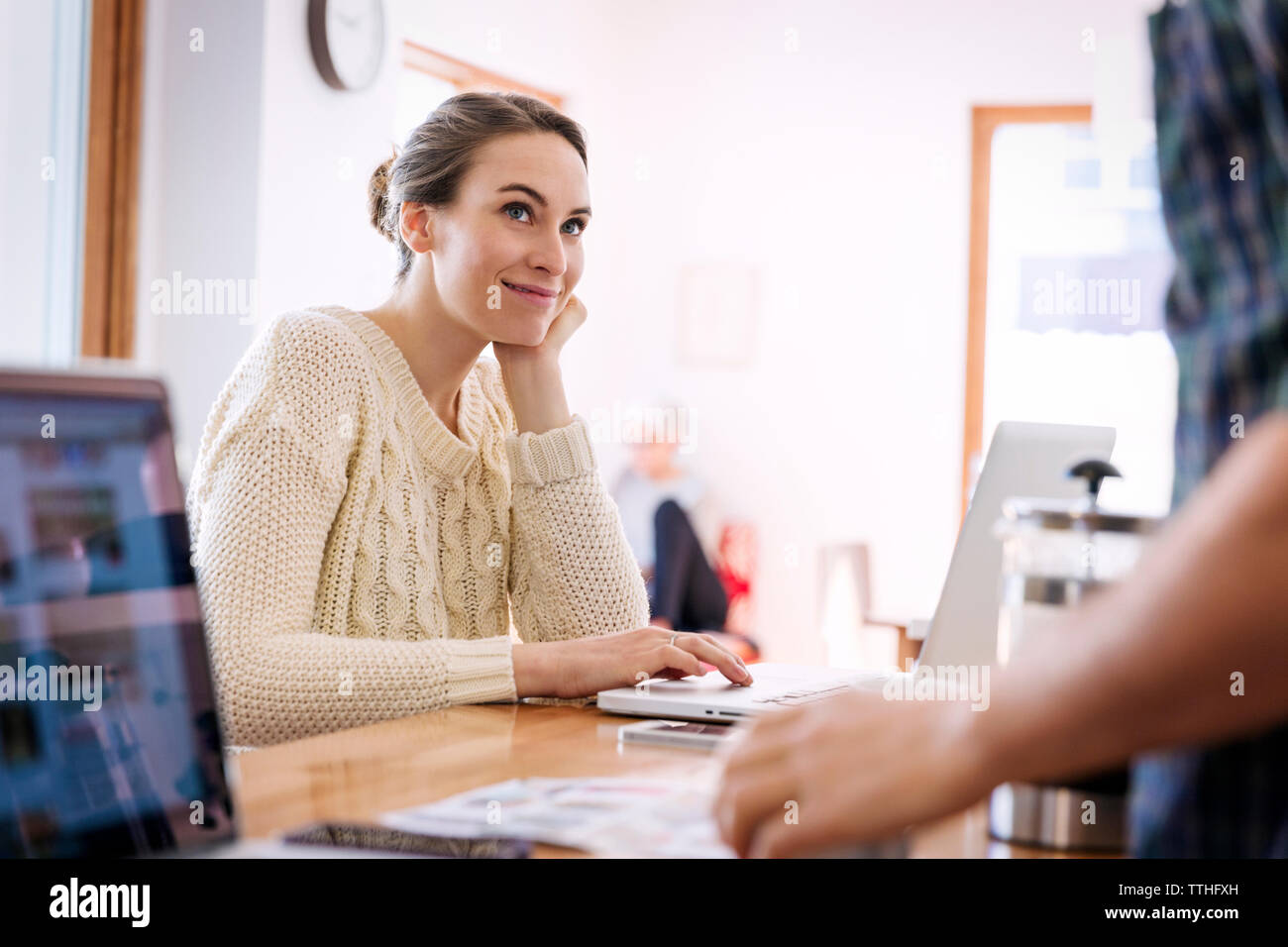 Smiling woman looking at man while using laptop at home Banque D'Images