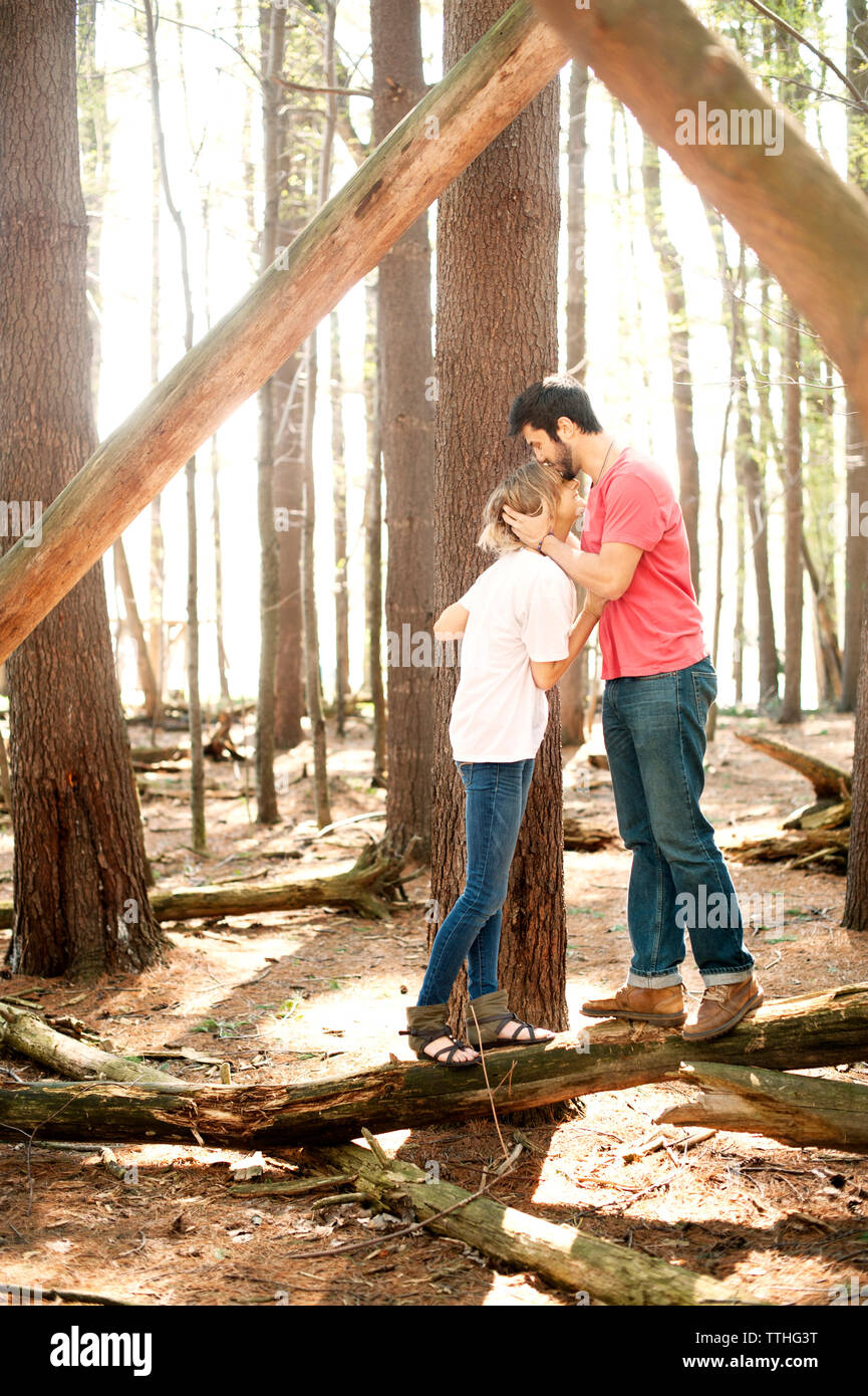 Side view of man kissing woman in forest Banque D'Images