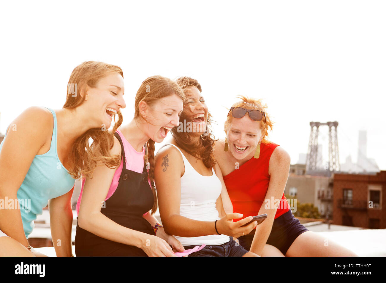 Rire des femmes lors de l'utilisation de phone sur la construction de terrasse en journée ensoleillée Banque D'Images
