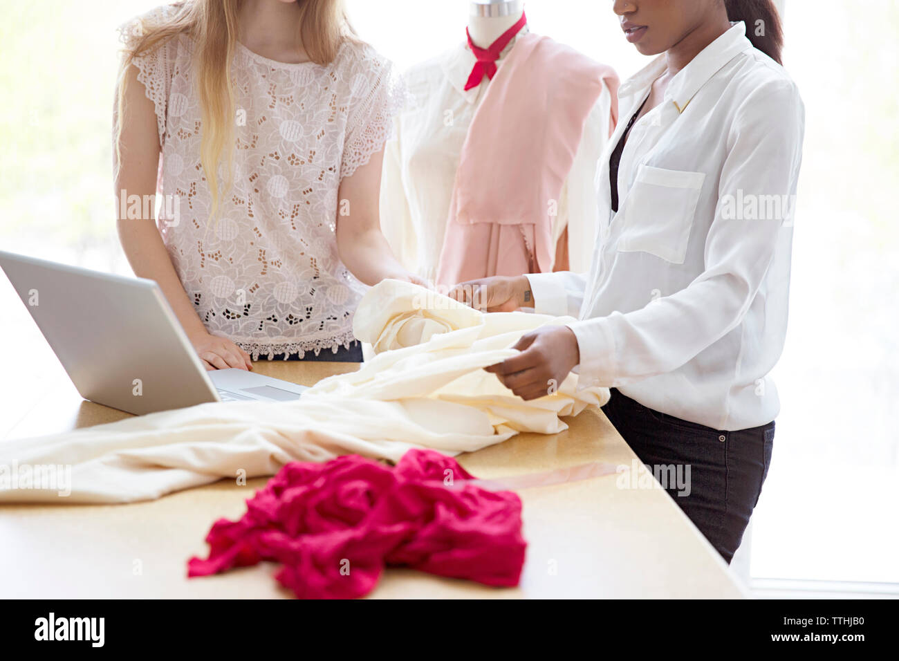 Portrait de femme tissu contrôle designers par laptop at desk Banque D'Images