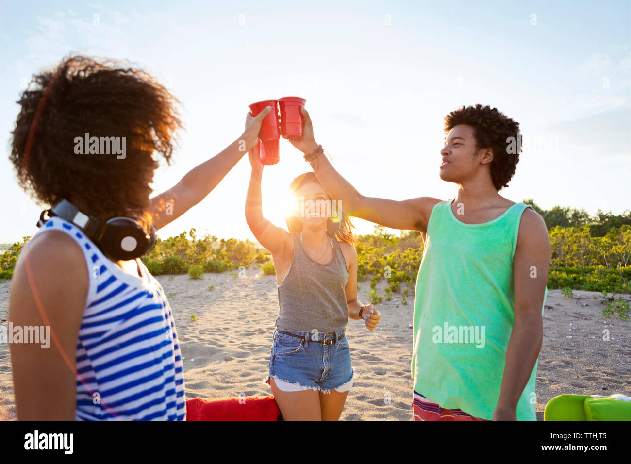 Happy friends toasting verre au soleil sur la plage Banque D'Images