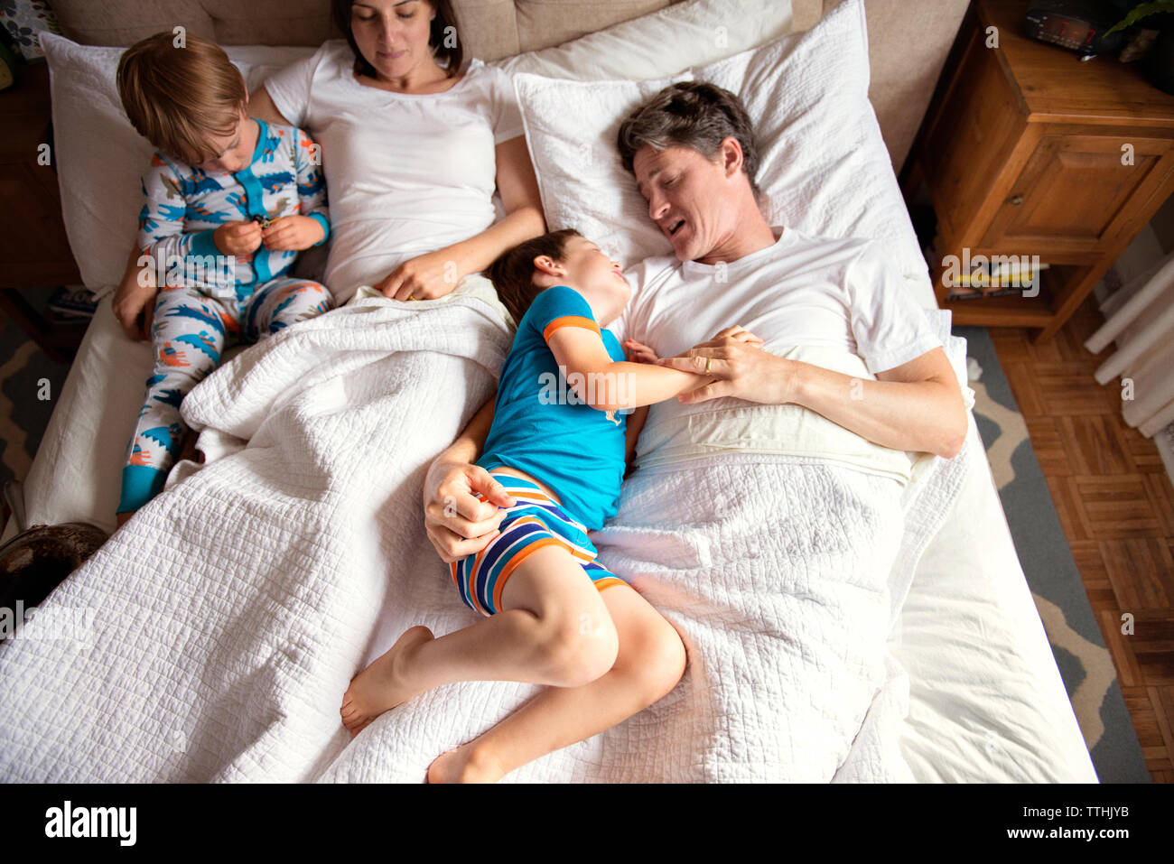 Vue de dessus de parents avec enfants se trouvant sur le lit chez lui Banque D'Images