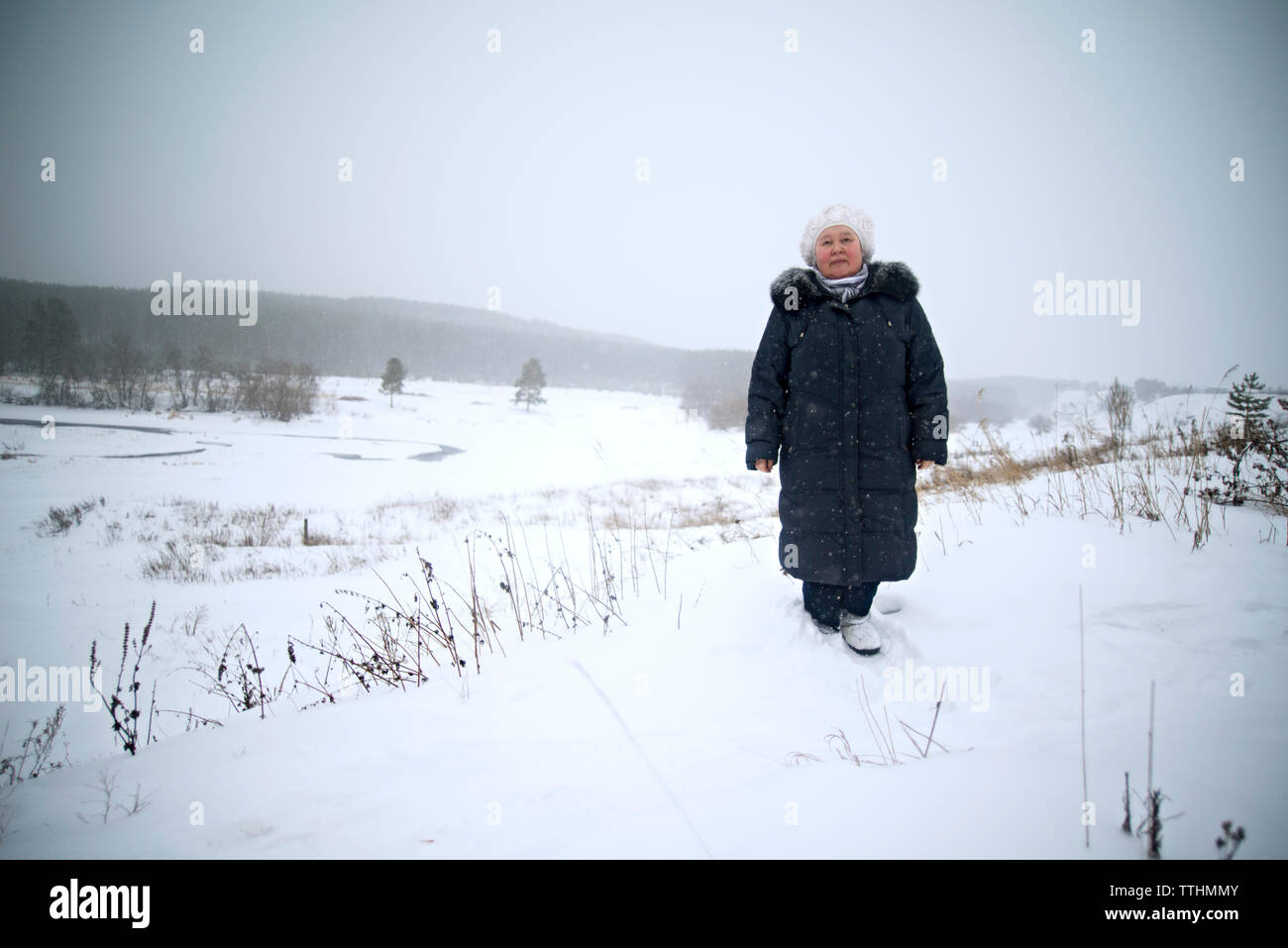 Portrait de femme en se tenant sur le terrain couvert de neige contre ciel clair Banque D'Images