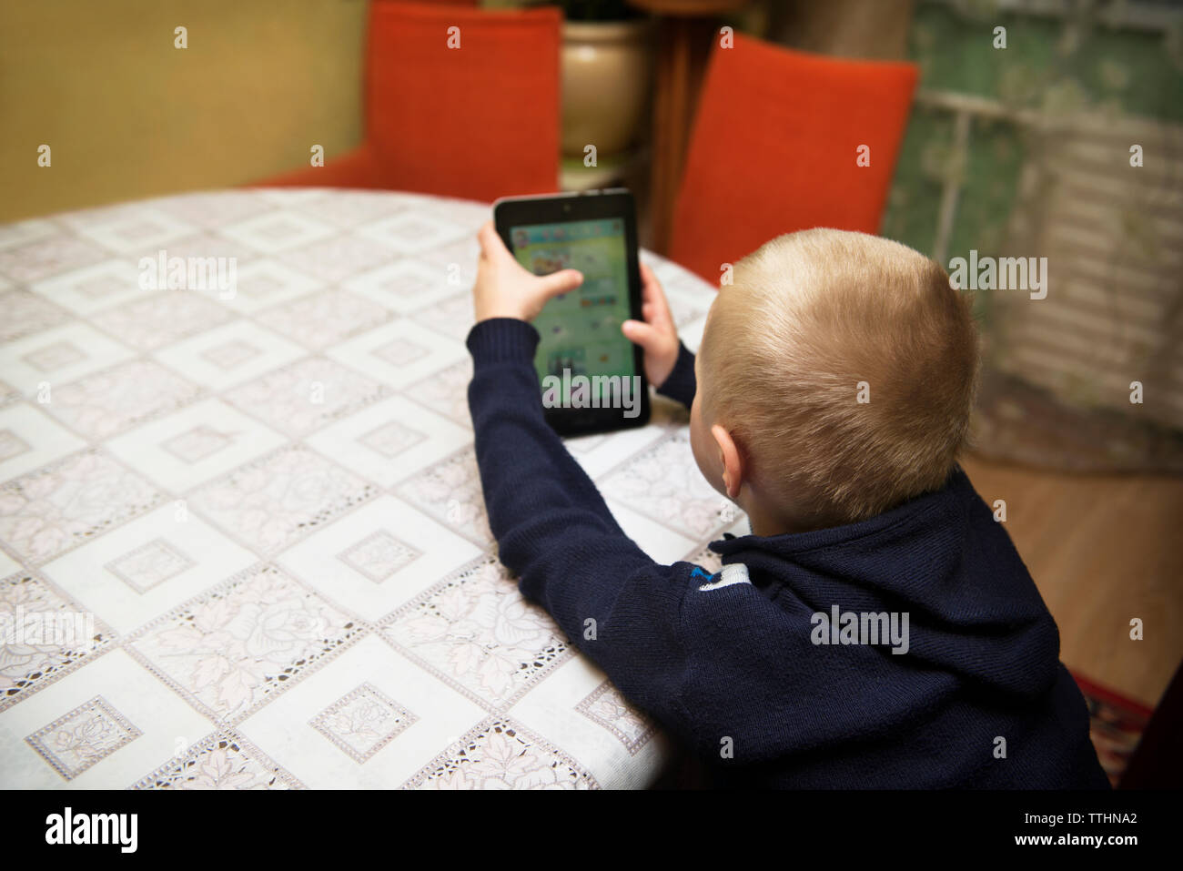 Boy using tablet computer while sitting at table Banque D'Images