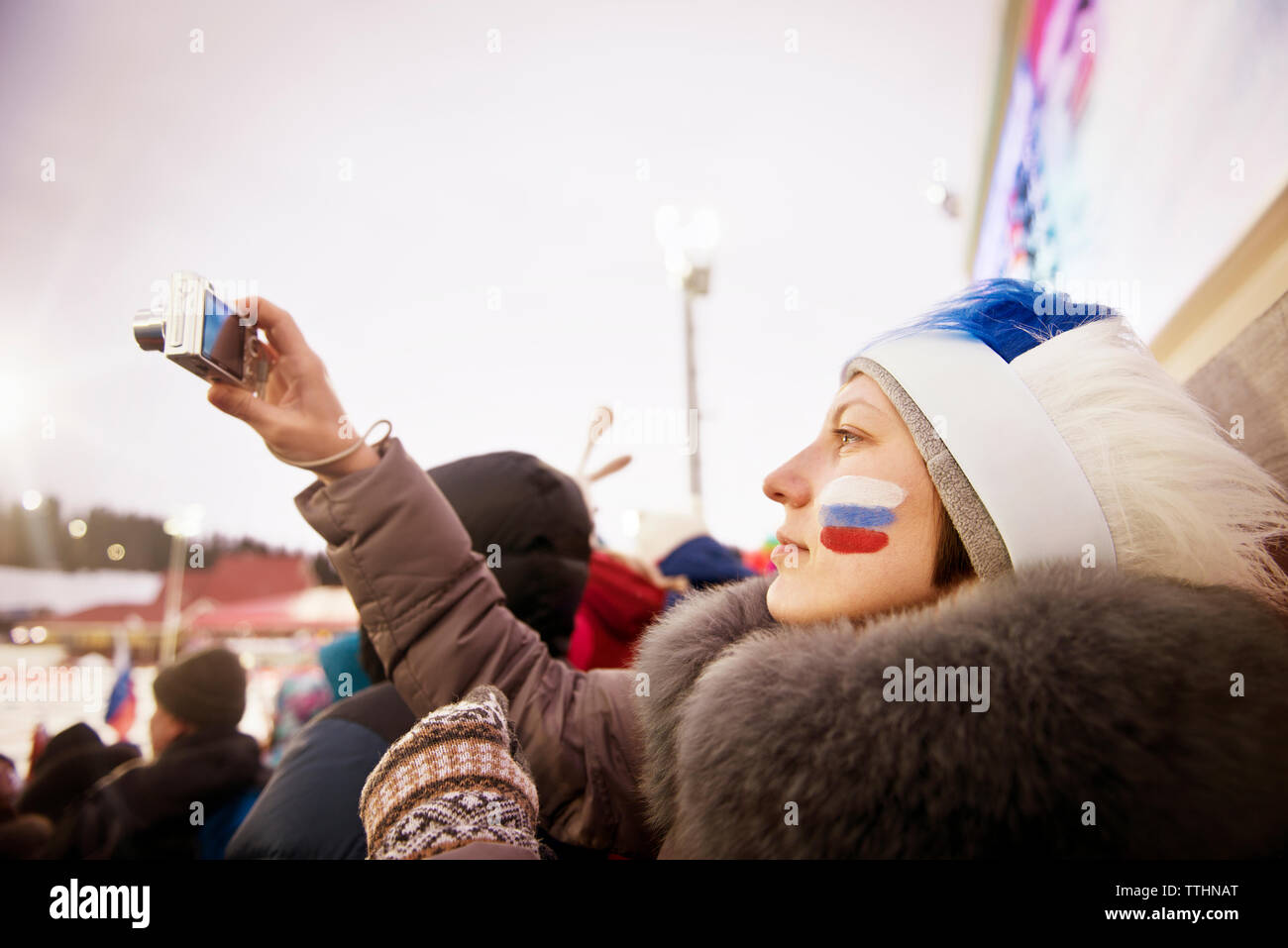 Femme Russe à travers un terrain de soccer fan photographie caméra contre ciel clair Banque D'Images