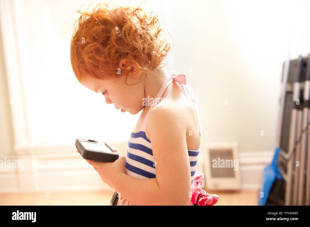 Vue de côté de fille à l'aide de la technologie tout en se tenant à la maison Banque D'Images