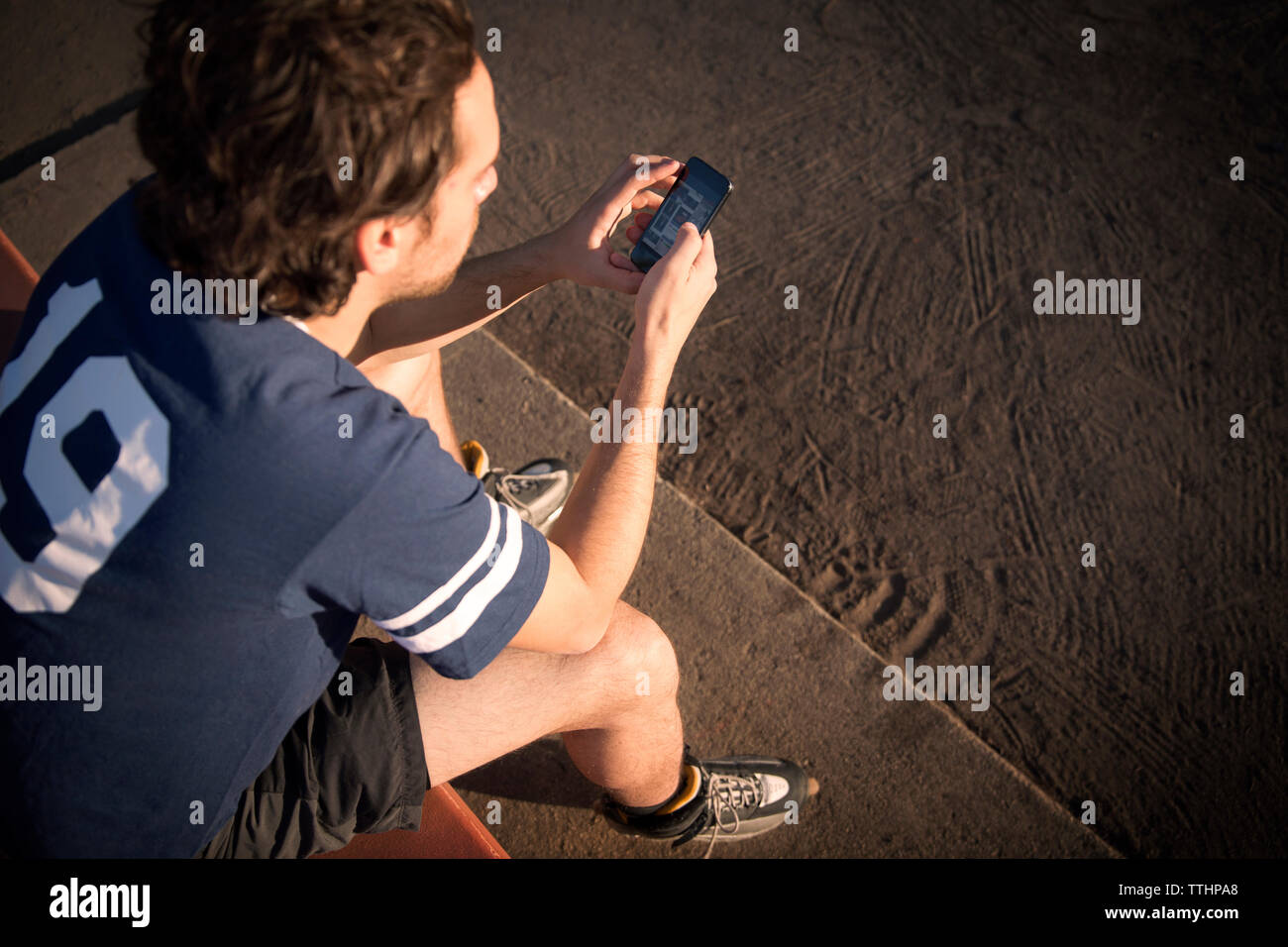 High angle view of roller hockey player using mobile phone while sitting on bench Banque D'Images