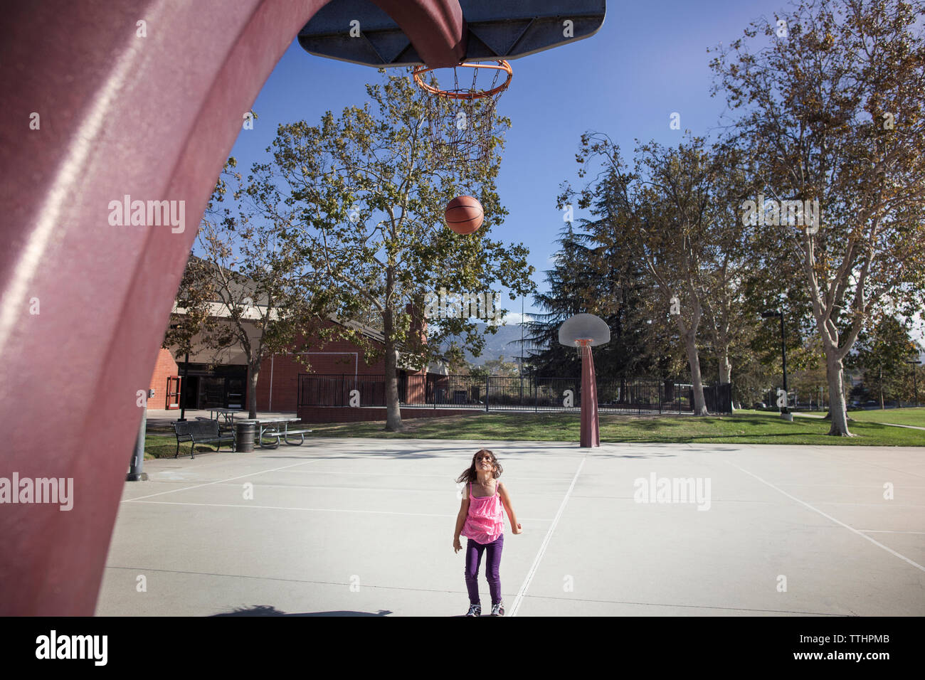Girl looking at ball tombant de basket-ball à la cour Banque D'Images