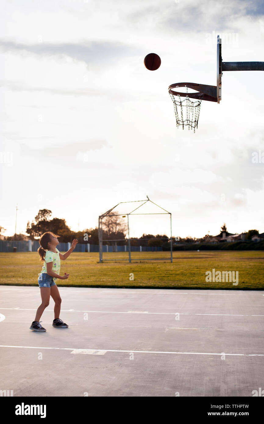 Girl playing basketball on court contre le ciel Banque D'Images