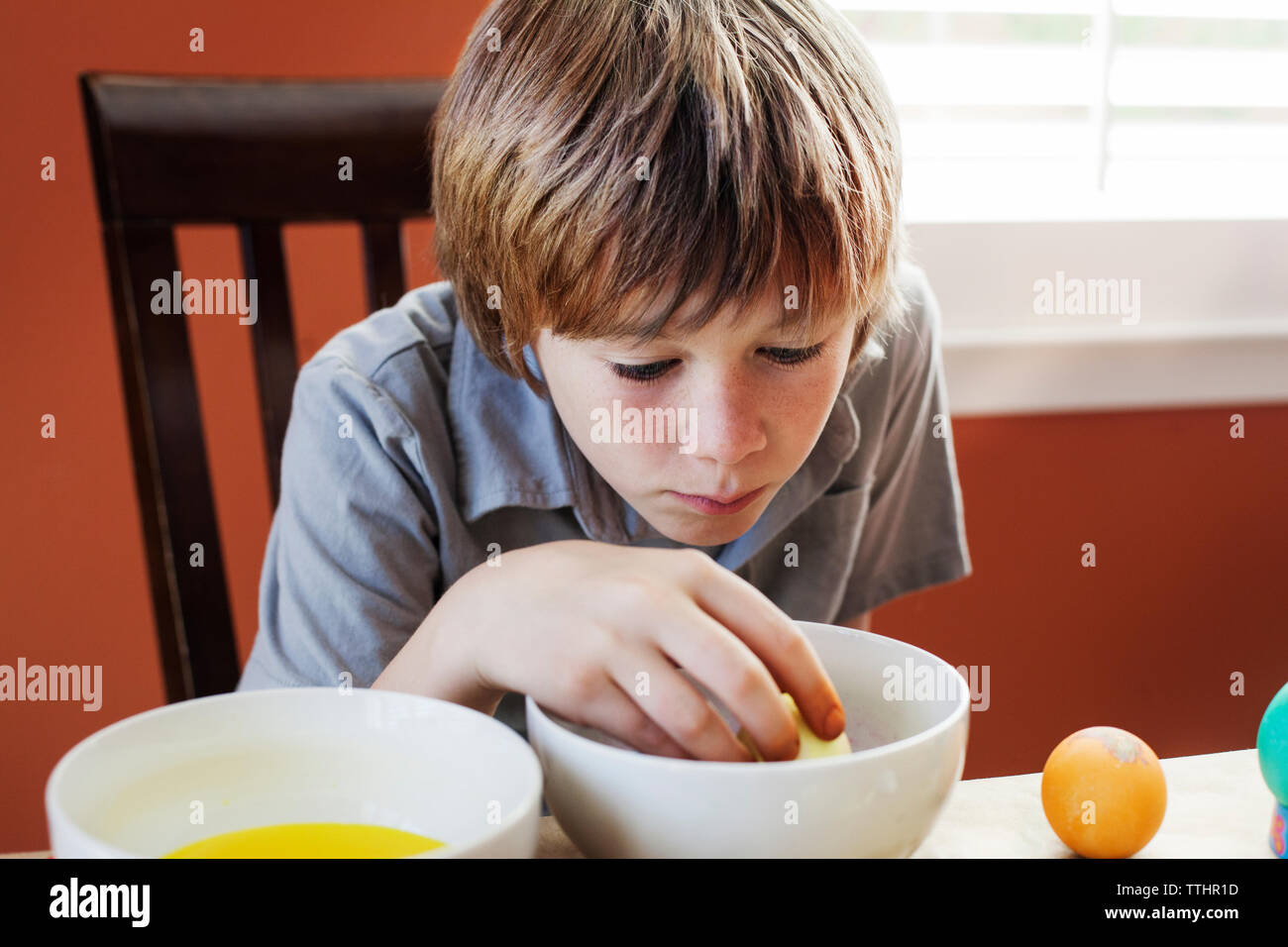 Garçon coloriant l'oeuf de pâques sur la table à la maison Banque D'Images
