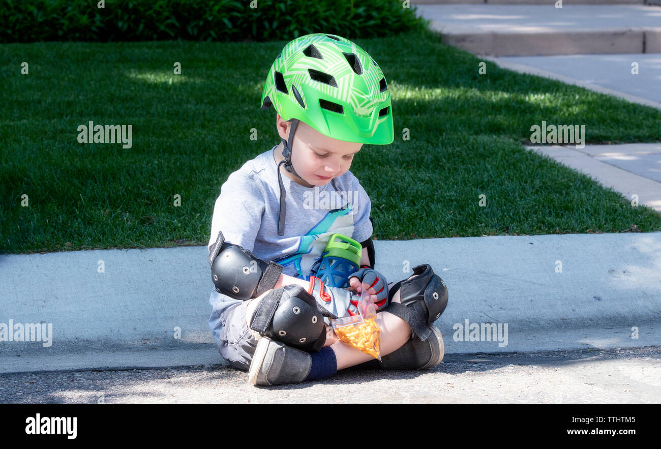 Enfant habillé en location du matériel de sécurité avec casque et gants  s'arrête pour un casse-croûte Photo Stock - Alamy