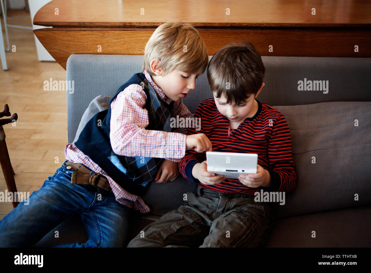 High angle view of siblings playing video game while sitting on sofa at home Banque D'Images
