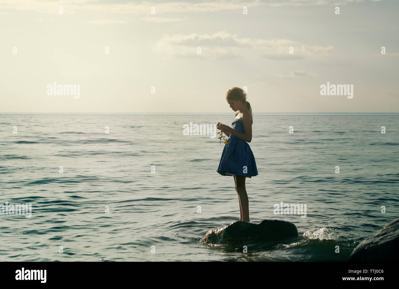 Girl holding plant en se tenant sur le rock en mer Banque D'Images