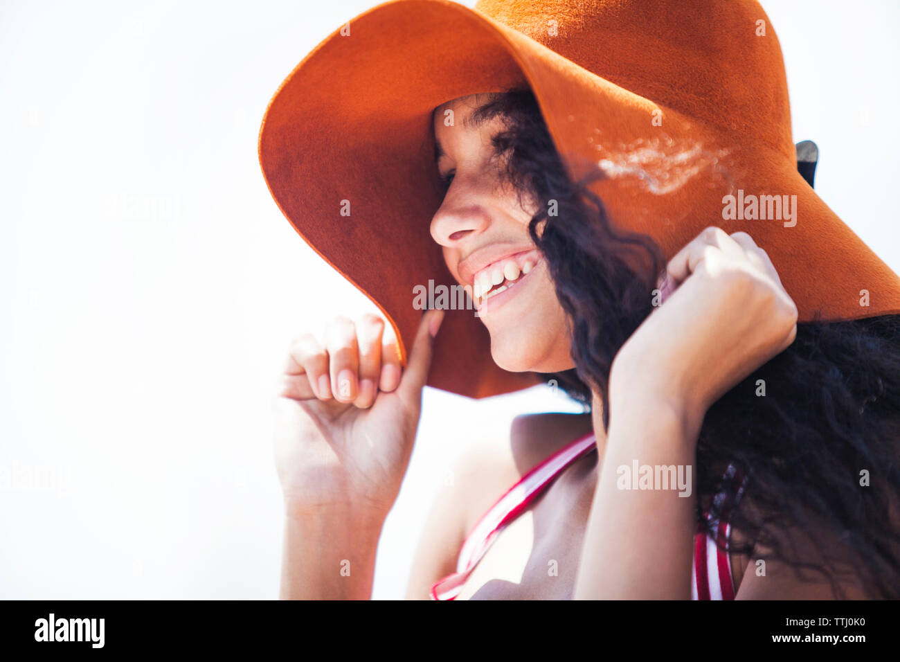 Fille avec chapeau de soleil à l'écart debout contre le ciel Banque D'Images