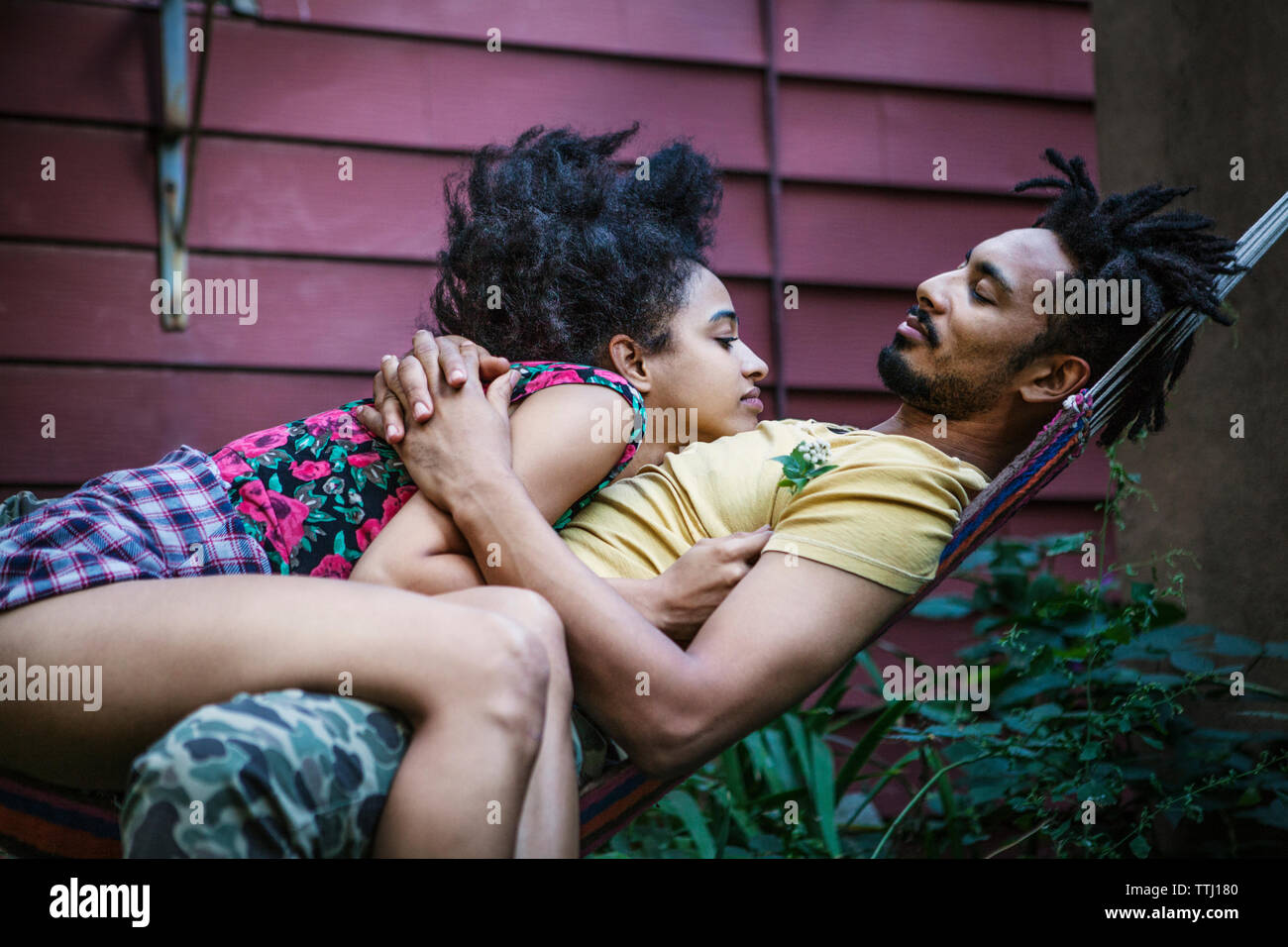 Couple relaxing on hammock in lawn Banque D'Images