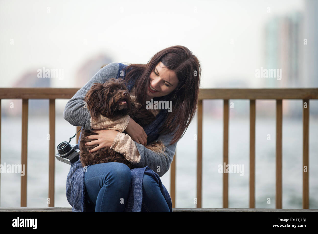 Woman looking at dog alors qu'il était assis sur le banc contre l'Hudson River Banque D'Images