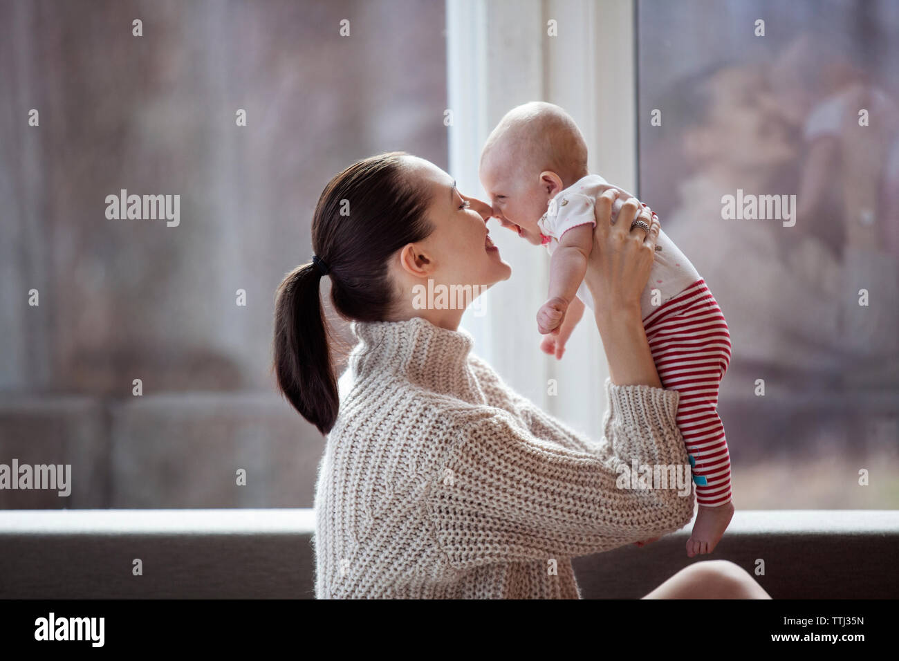 Vue latérale d'happy woman rubbing nose with baby girl at home Banque D'Images
