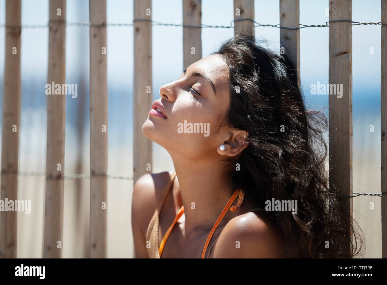Femme assise détendue contre clôture à beach Banque D'Images