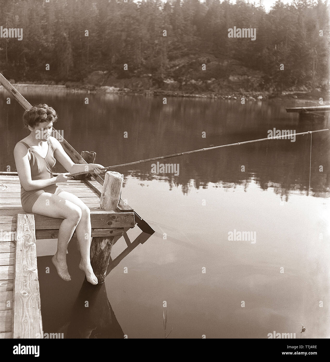 La pêche dans les années 1950. Une jeune femme portant un maillot de bain est la pêche. Kristoffersson ref K51-4 Suède 1945 Banque D'Images