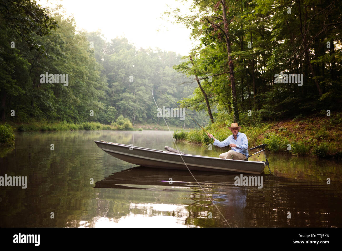 Casting homme canne à pêche alors que la pêche dans le lac Banque D'Images