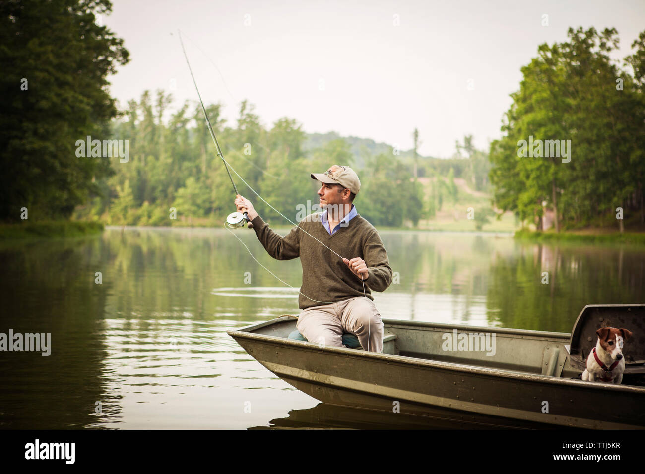 Casting homme canne à pêche alors que la pêche dans le lac Banque D'Images