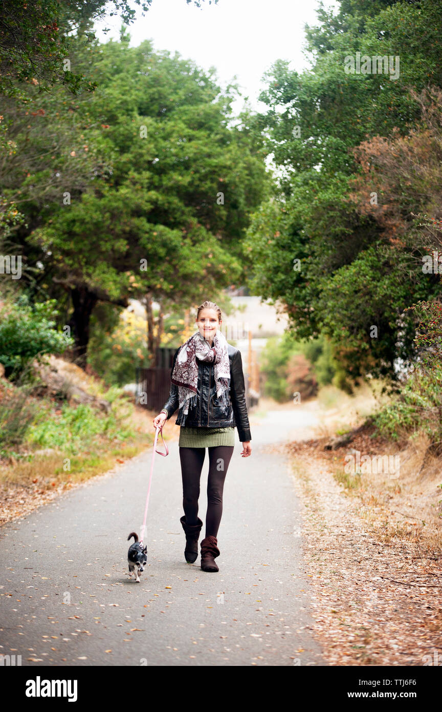 Portrait de femme avec dog walking on road Banque D'Images