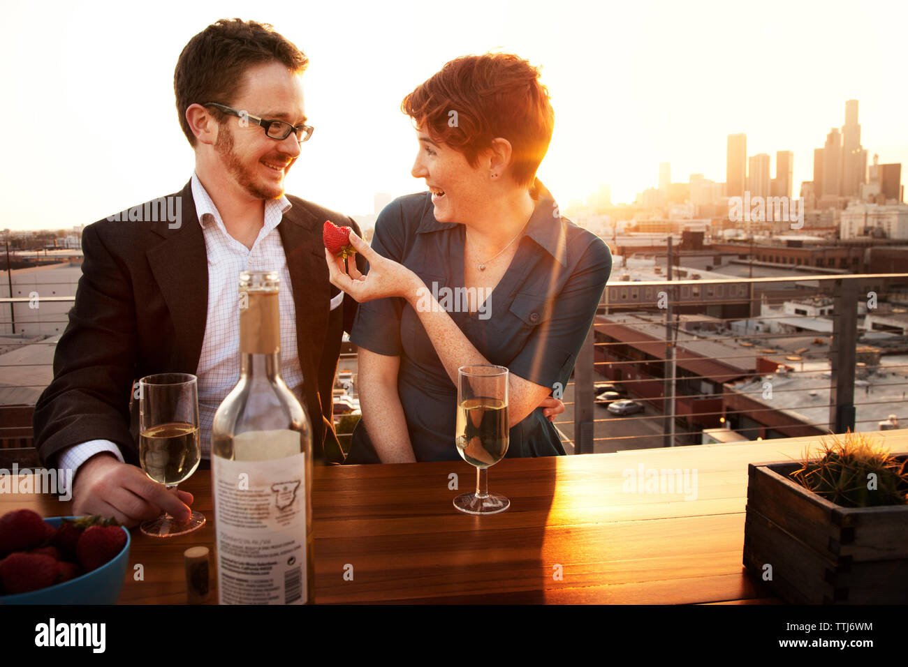 Man smiling girlfriend holding strawberry in restaurant Banque D'Images