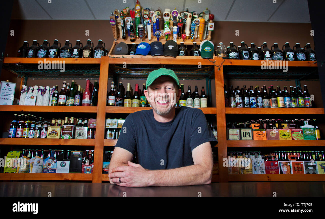 Portrait de propriétaire s'appuyant sur table au Liquor Store Banque D'Images