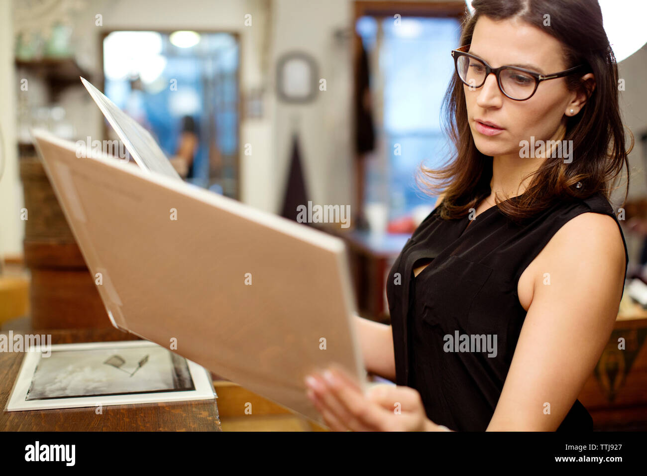 Woman looking at photographs debout en magasin Banque D'Images