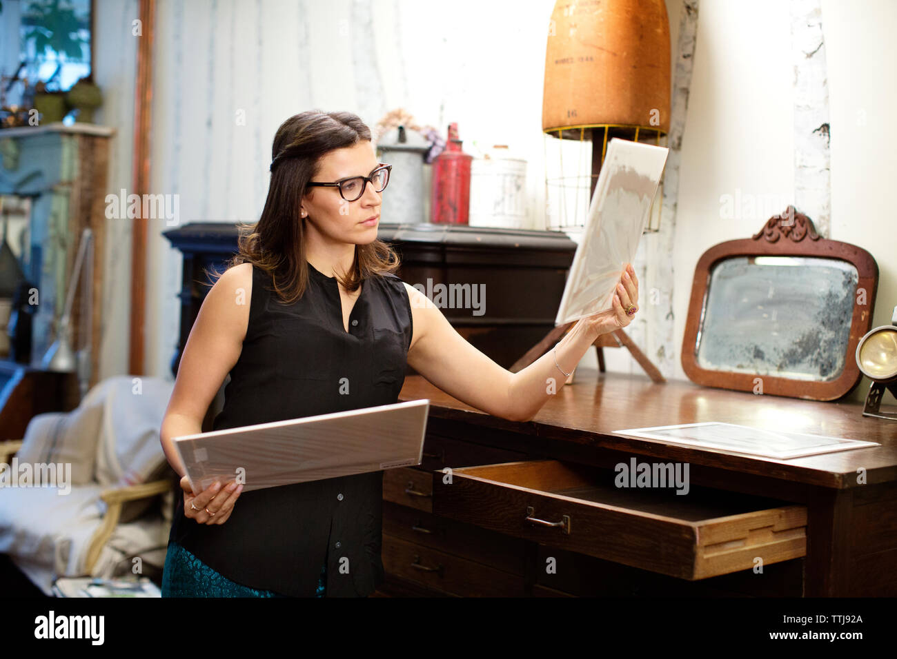Woman looking at photographs debout par tiroir dans store Banque D'Images