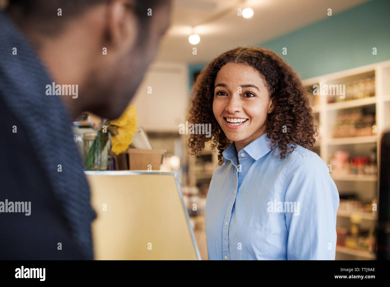 Happy woman looking at client tandis que l'article en magasin Banque D'Images