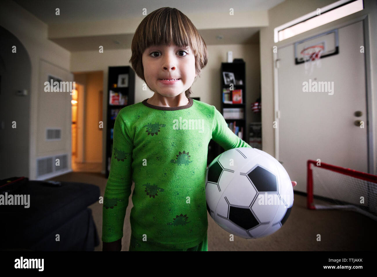 Portrait of boy holding soccer ball tout en se tenant à la maison Banque D'Images