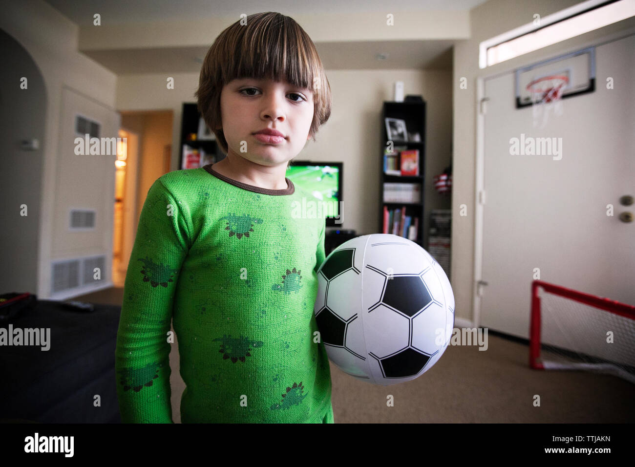 Boy holding soccer ball tout en se tenant à la maison Banque D'Images
