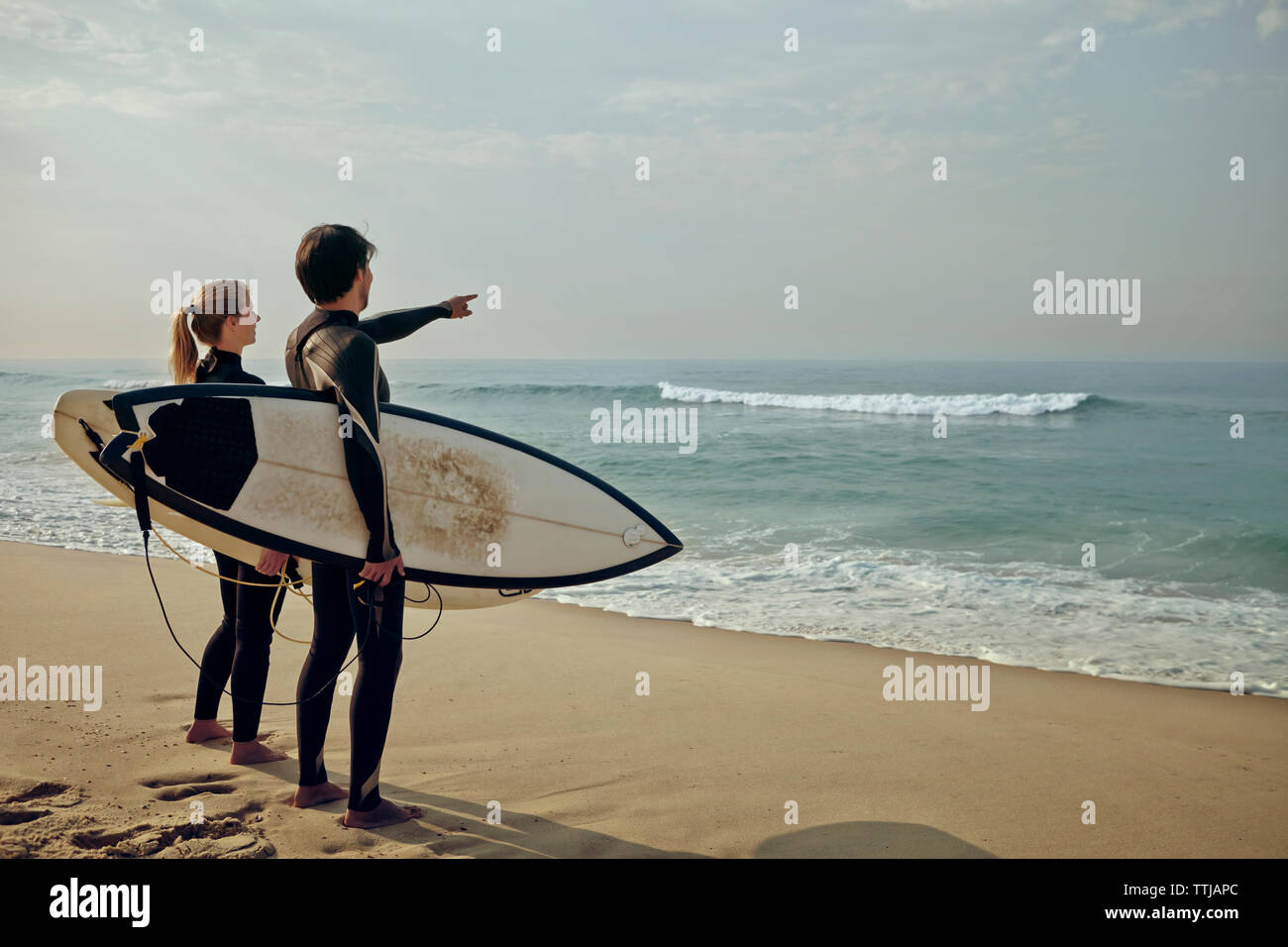 Couple à la recherche en mer dans l'exercice surfboard at beach Banque D'Images