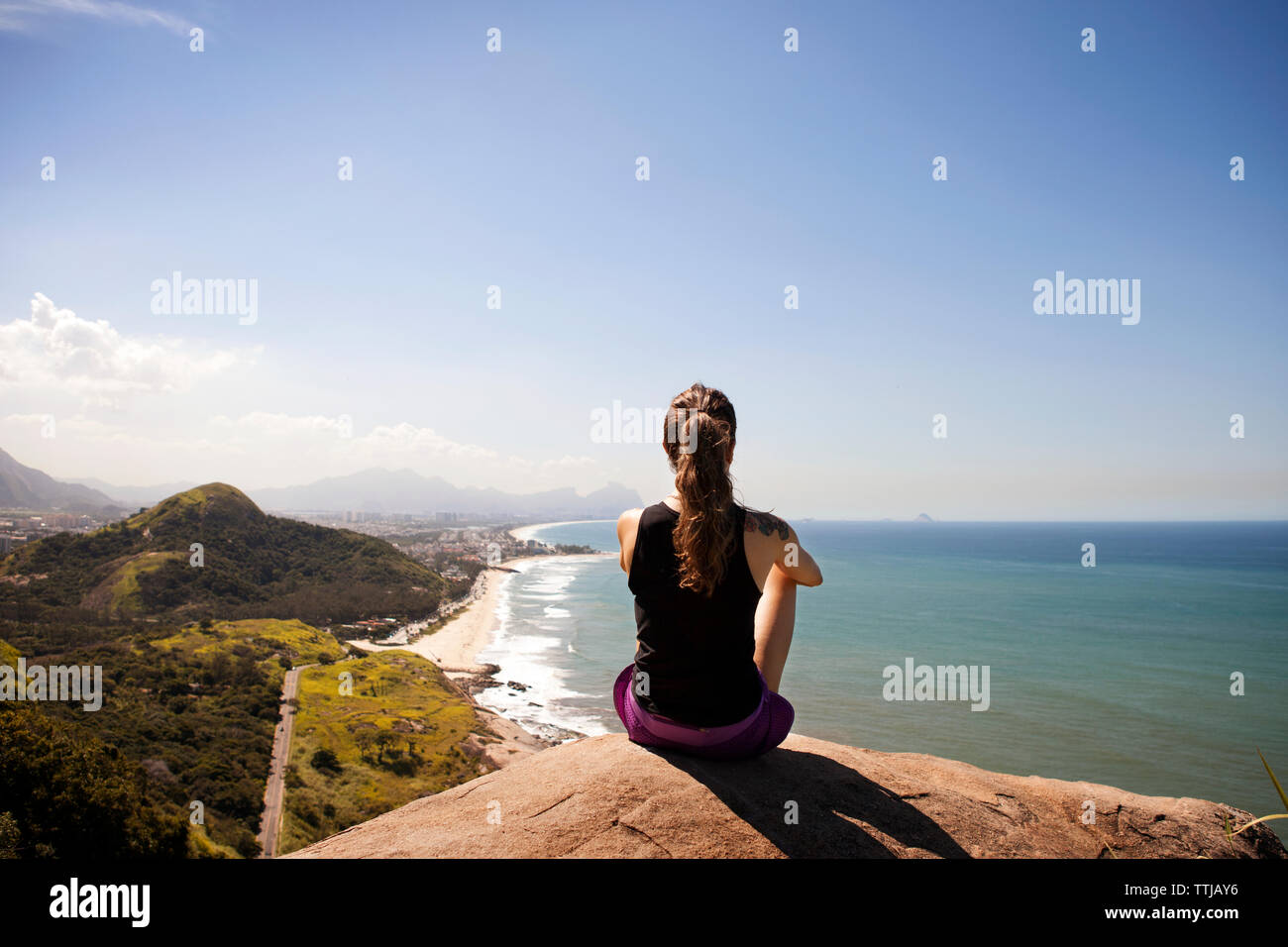 Rear view of woman sitting on rock et looking at view Banque D'Images