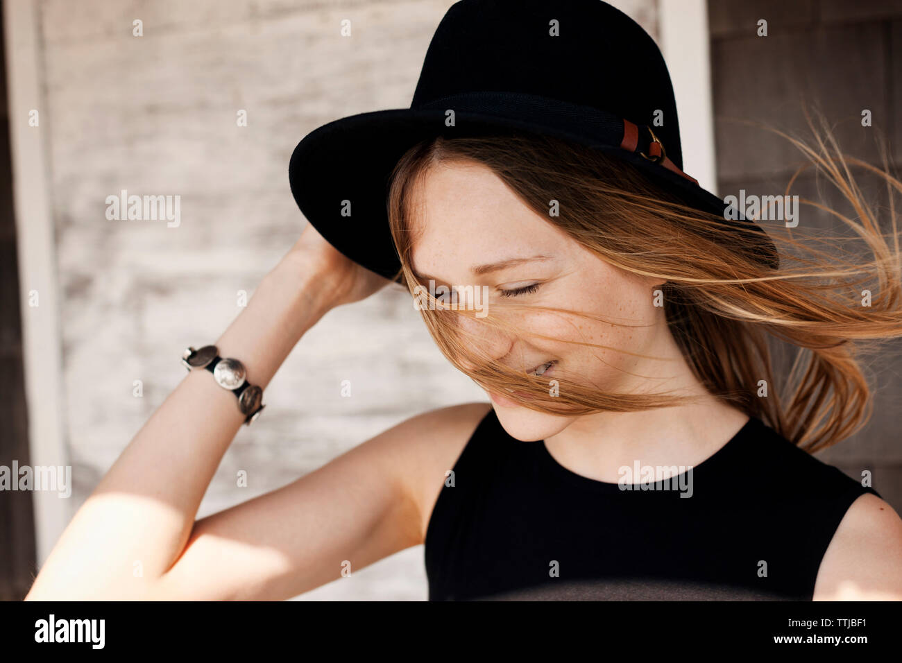 Woman holding sun hat contre mur en bois Banque D'Images