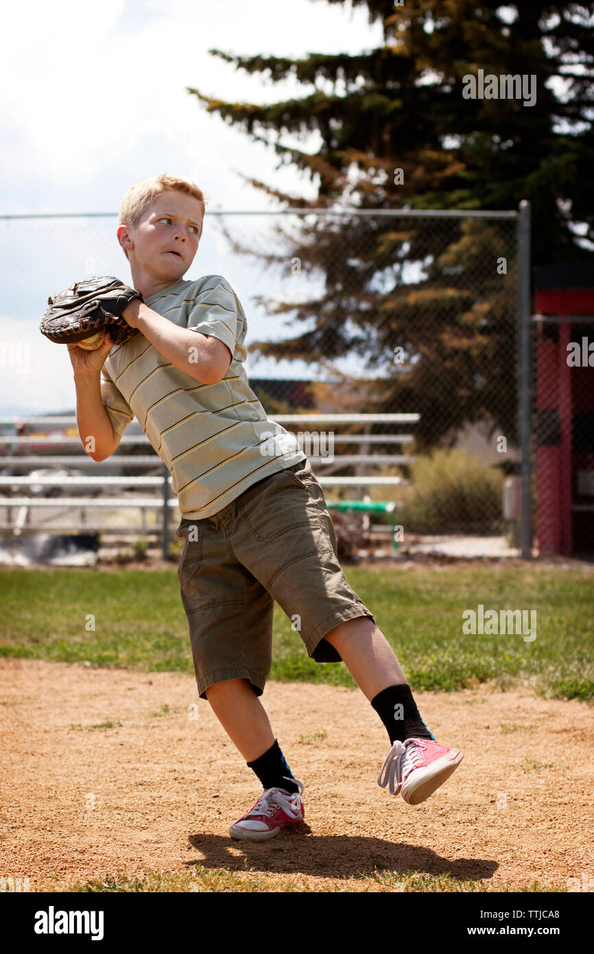Boy throwing ball tout en se tenant au champ de base ball Banque D'Images