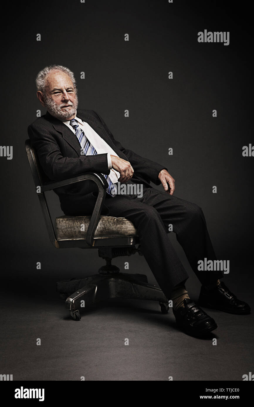 Portrait of senior woman sitting on office chaise contre fond noir Banque D'Images