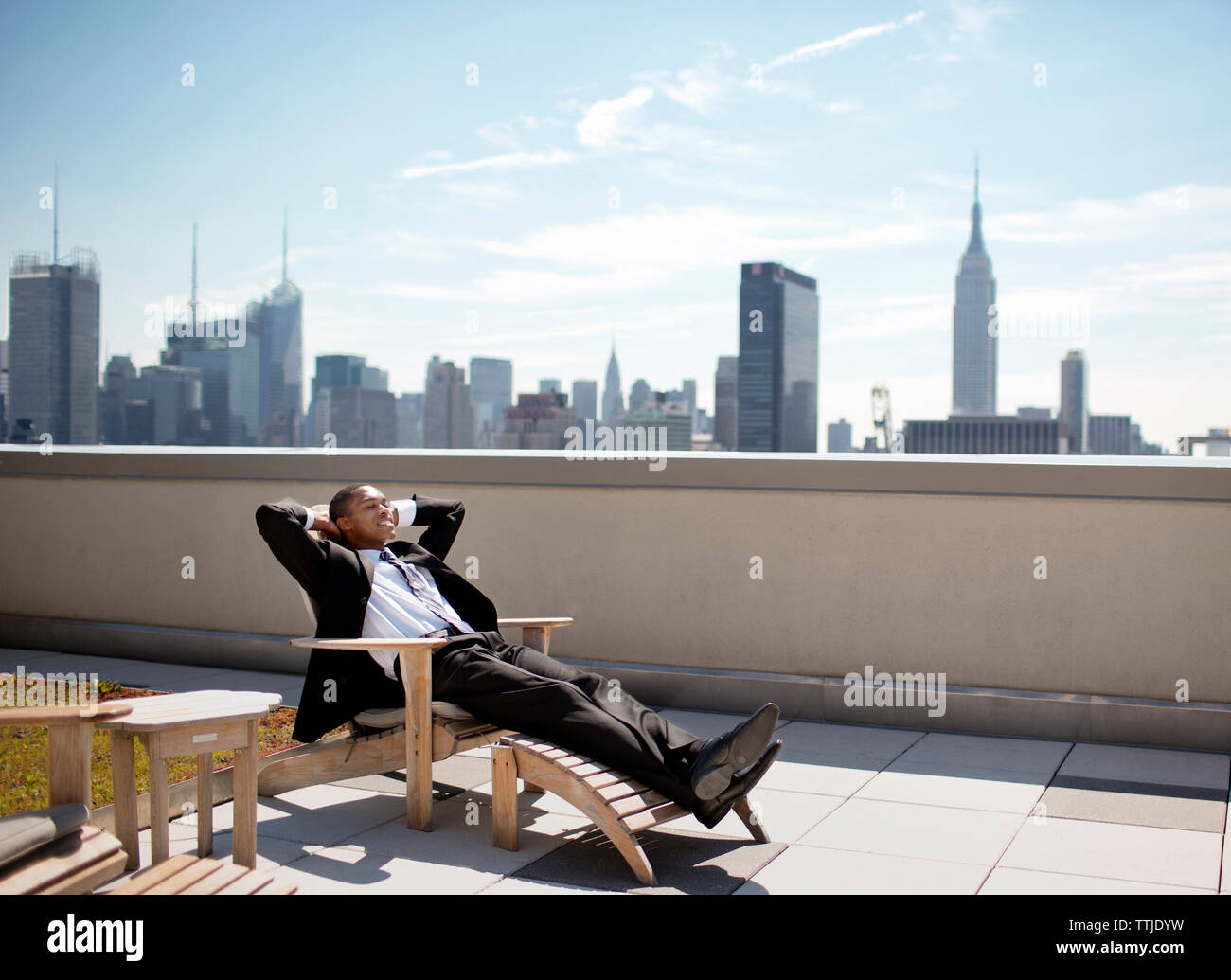 homme d'affaires se relaxant sur la chaise longue contre le ciel Banque D'Images