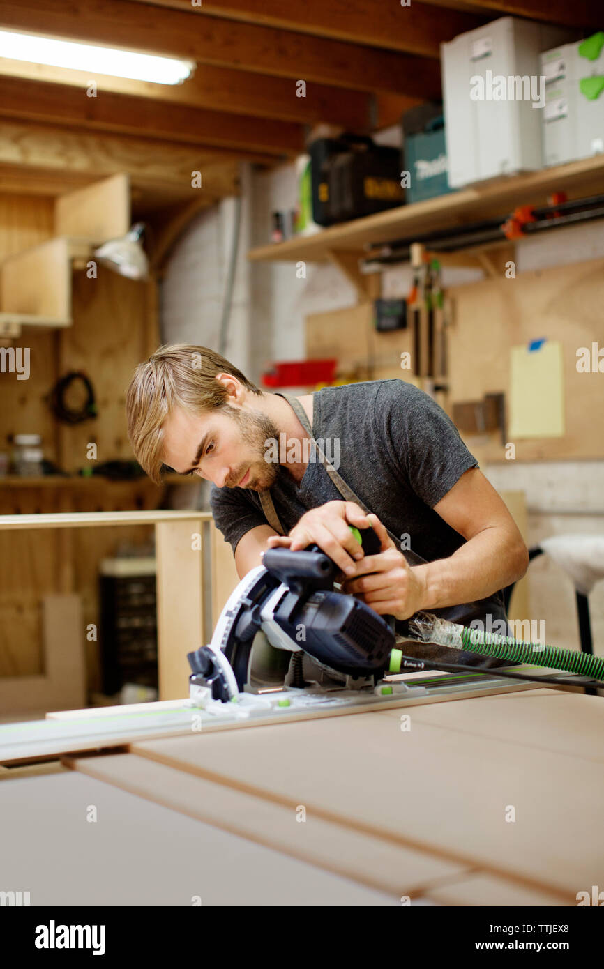 travailleur travaillant avec un outil électrique dans un atelier de menuiserie Banque D'Images
