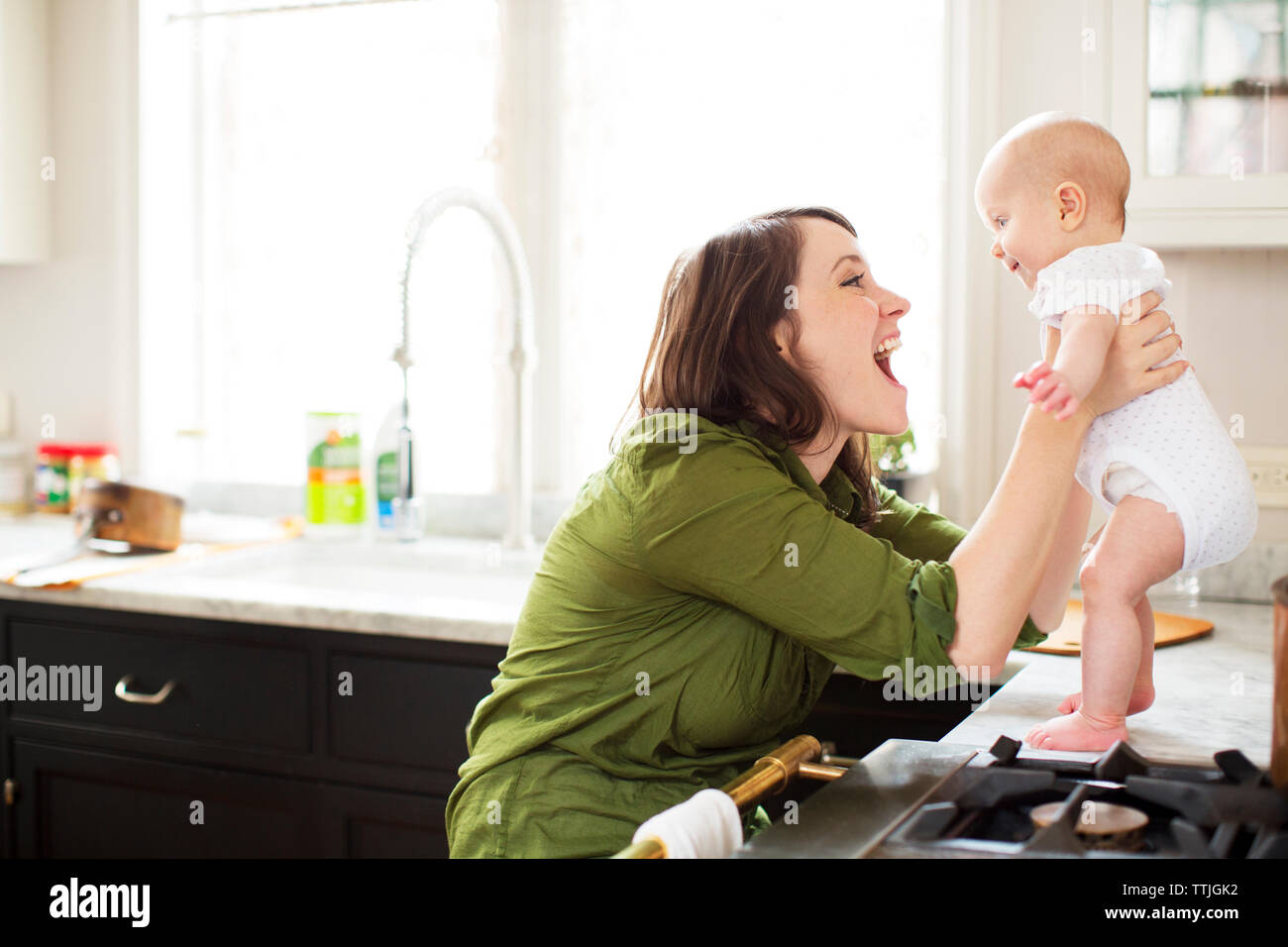 Heureuse mère jouant avec bébé fille dans la salle de bains Banque D'Images