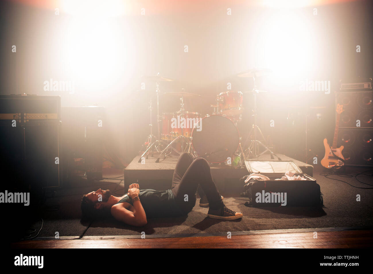 Side view of man lying on floor in rock music studio Banque D'Images