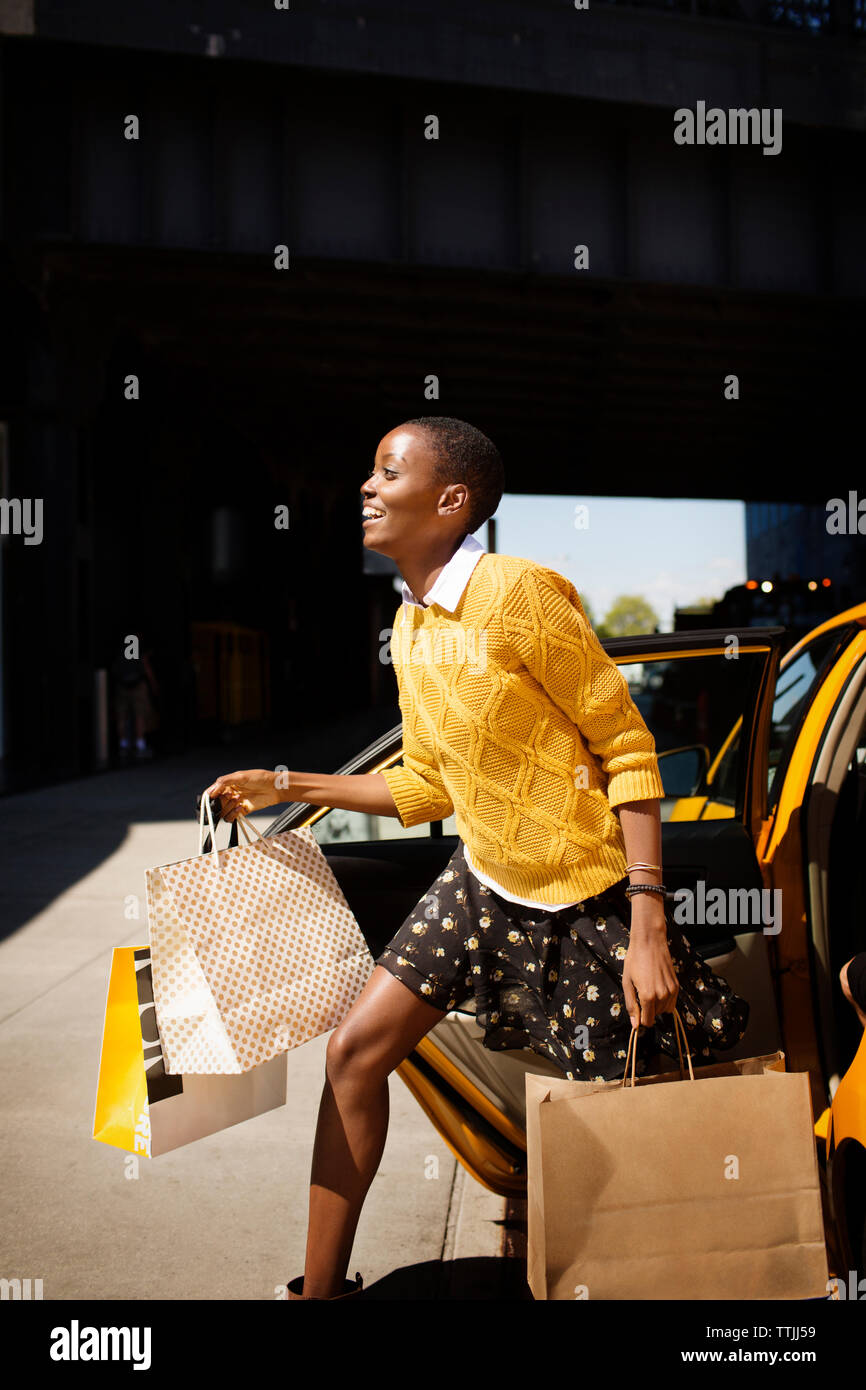 Woman carrying shopping bags sortir de taxi Banque D'Images