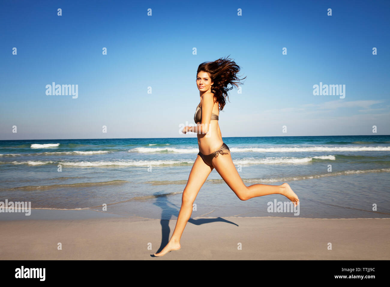 Portrait of woman in bikini tournant au beach contre ciel clair Banque D'Images